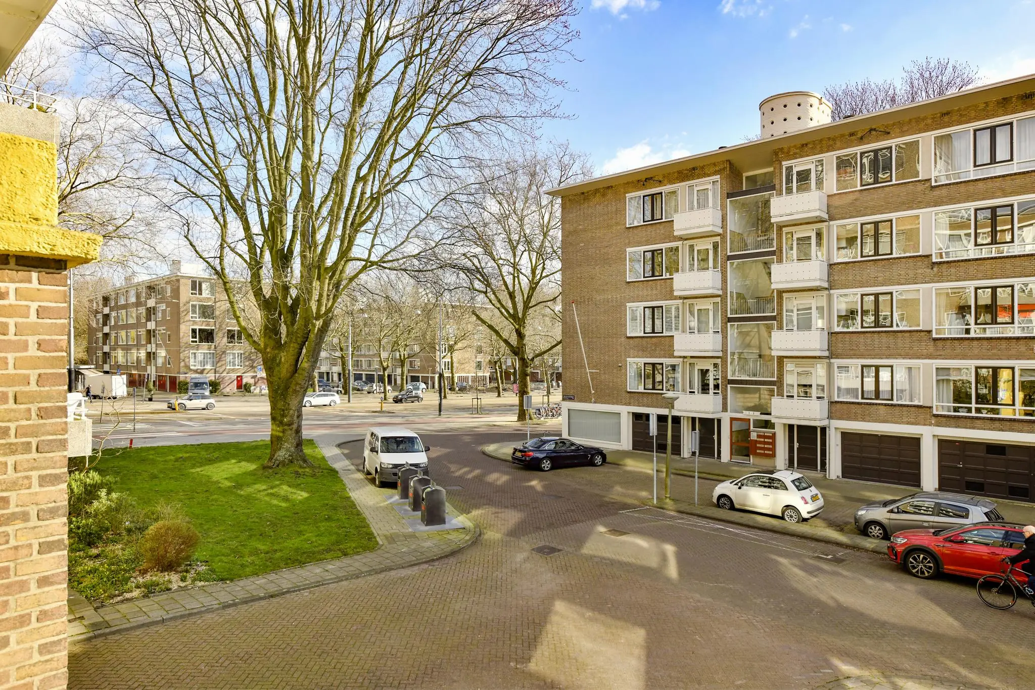 Appartementengebouw aan de Cornelis Dopperkade met geparkeerde auto's, een grasveld en bomen in een rustige straat.